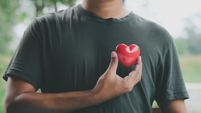 Man who is healthy holding a heart to show that he got his heart health tests done at a men's health clinic